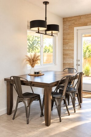 A dining area with a large wooden table, four chairs, and a pendant light fixture. - Downtown, Stargazing Deck, Fire Pit, Record Player, Games (Joshua Tree)
