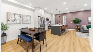 Uma cozinha moderna com armários brancos, eletrodomésticos de aço inoxidável e uma ilha central.