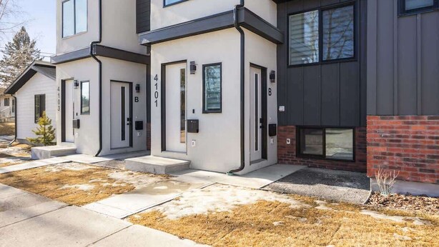 A modern two-story residential building with a flat roof, large windows, and a brick accent wall. - Steps to Transit • Bright Kitchen • Parks & Shops (Calgary)