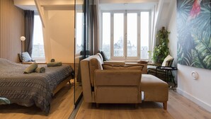 A modern bedroom with a bed, a sofa, and a large window with a city view. - Canal view home in the heart of Amsterdam (Amsterdam)