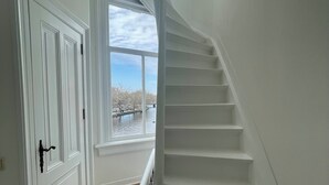 A staircase with white walls and a wooden floor leading to a second floor. - Canal view home in the heart of Amsterdam (Amsterdam)