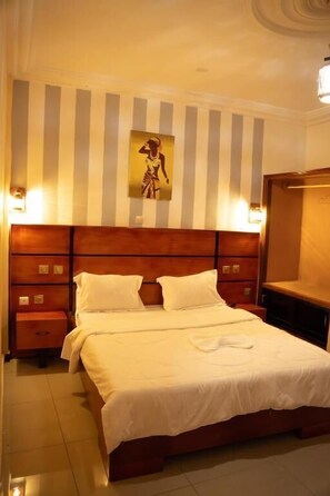 Een hotelkamer met een groot bed, een houten hoofdeinde en gestreept behang.