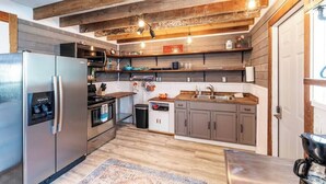 A modern kitchen with wooden beams, stainless steel appliances, and a farmhouse aesthetic. - Spacious Barn Apt w/ King Bed (Asheville)