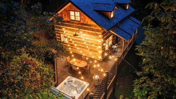 A log cabin with a hot tub and string lights on the deck. - Romantic Asheville Log Cabin w/ Hot Tub & Gym (Asheville)