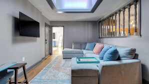 Ein modernes Wohnzimmer mit einer Couch, einem Flachbildfernseher, einem Oberlicht und Blick auf den angrenzenden Raum.