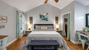 Ein Schlafzimmer mit einem Bett, Nachttischen, einem Deckenventilator, einem Schreibtisch und einem Sessel.