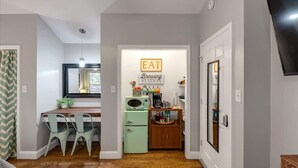 A compact kitchen with a dining area, a small refrigerator, and a coffee station. - Farm Suite, King bed, firepit, BBQ grill, animals! (Asheville)