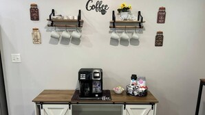 Eine Kaffeestation mit Kaffeemaschine, Tassen und einer Wanddekoration zum Kaffeethema.