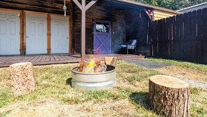 Eine Holzhütte mit nummerierten Türen, einem Feuerkorb und einer überdachten Veranda.