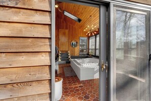 A modern bathroom with a large bathtub, wooden walls, and a tiled floor. - Asheville Farm Retreat, hot tub, King bed, firepit (Asheville)
