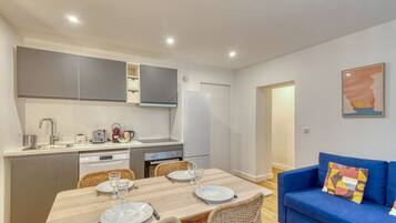 Un espace de vie compact comprenant un coin repas, une kitchenette et un canapé.