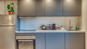 Eine moderne Küche mit Edelstahlgeräten, einem eingebauten Backofen und einer Arbeitsplatte mit Wasserkocher, Toaster und weiteren kleinen Geräten.