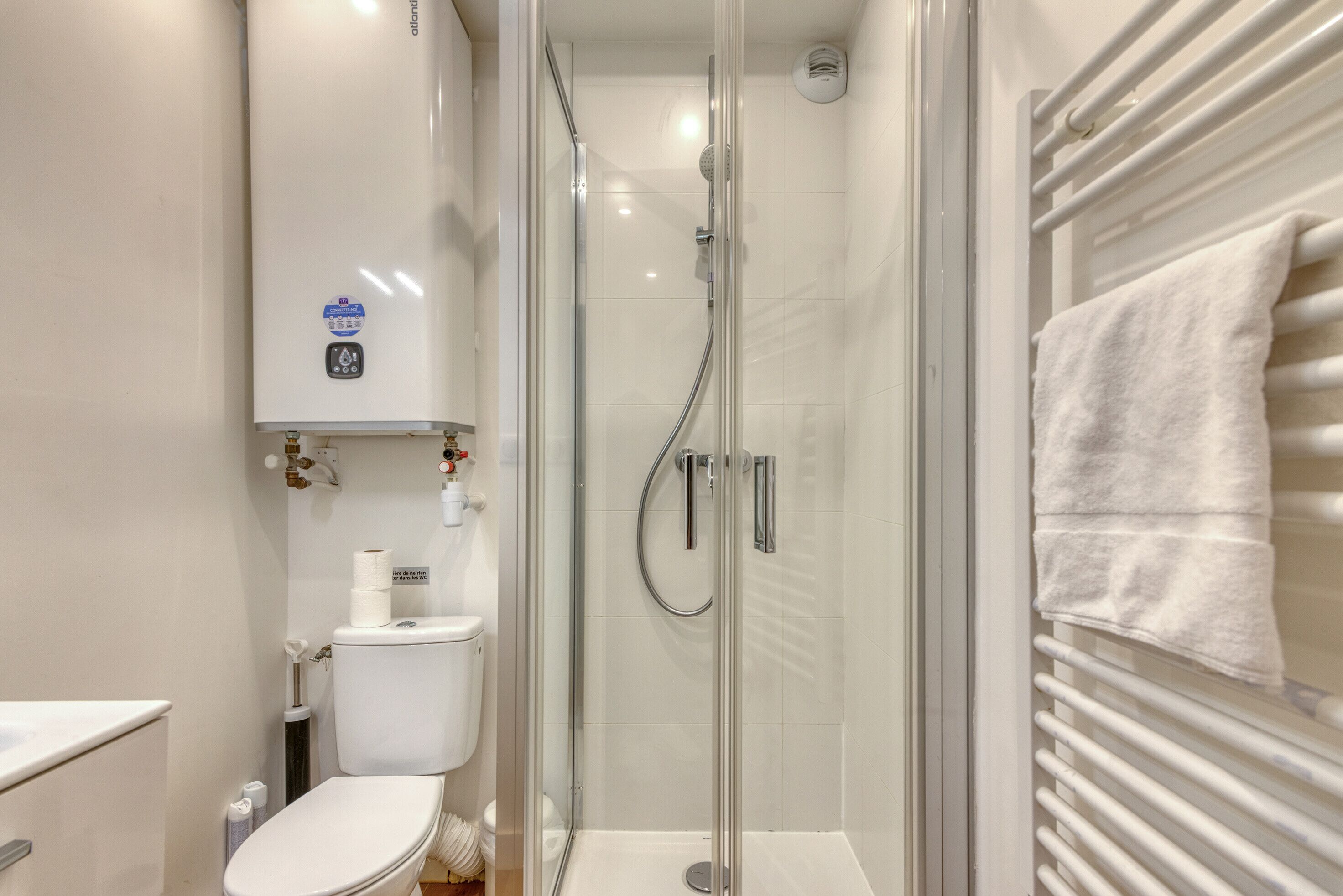 Une salle de bain moderne avec une douche à parois de verre, des toilettes et un porte-serviettes.