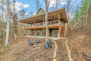 A two-story cabin with a balcony, outdoor seating, and a stone pathway. - Mcdonald Lakeside Cottage (Sevierville)