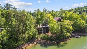 A house surrounded by dense greenery and a body of water. - Mcdonald Lakeside Cottage (Sevierville)
