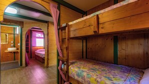 A wooden cabin interior with bunk beds, a bathroom with a sink, and a window with curtains. - Camping Laplaya Ibiza (Santa Eulalia del Rio)