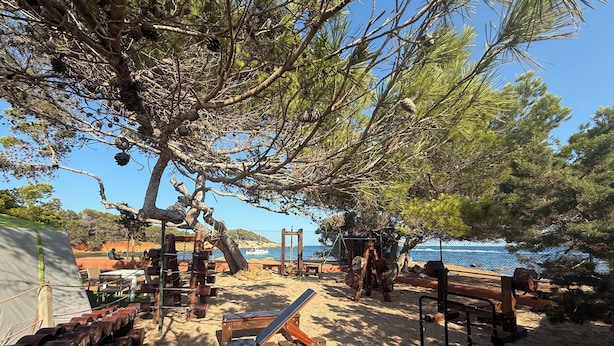 A beachside gym with exercise equipment, a tent, and a view of the sea. - Camping Laplaya Ibiza (Santa Eulalia del Rio)