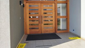 A wooden double door with glass panels, a black mat at the entrance, and a yellow sign on the floor. - Modern, impeccable, close to terminals in the city of Temuco. (Temuco)