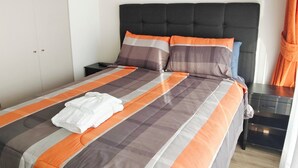 A neatly made bed with a striped bedspread, a black headboard, and a white towel on the bed.