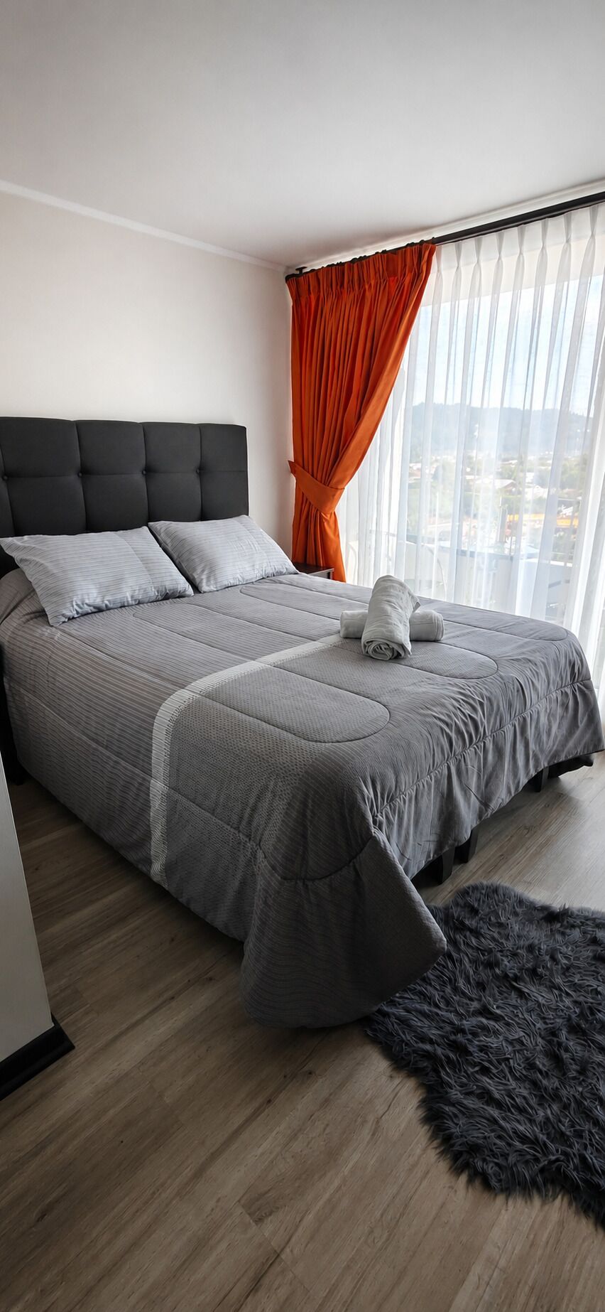 Une chambre à coucher avec un lit, une fenêtre avec des rideaux et une vue sur l’extérieur.