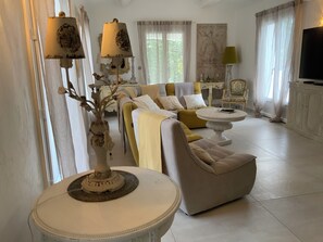 Un salon comprenant un canapé, des fauteuils, une table basse et un téléviseur.