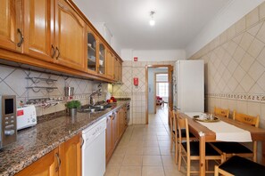 Une cuisine avec des meubles de rangement en bois, un plan de travail sur lequel se trouvent un grille-pain et un évier, ainsi qu’une plante en pot.