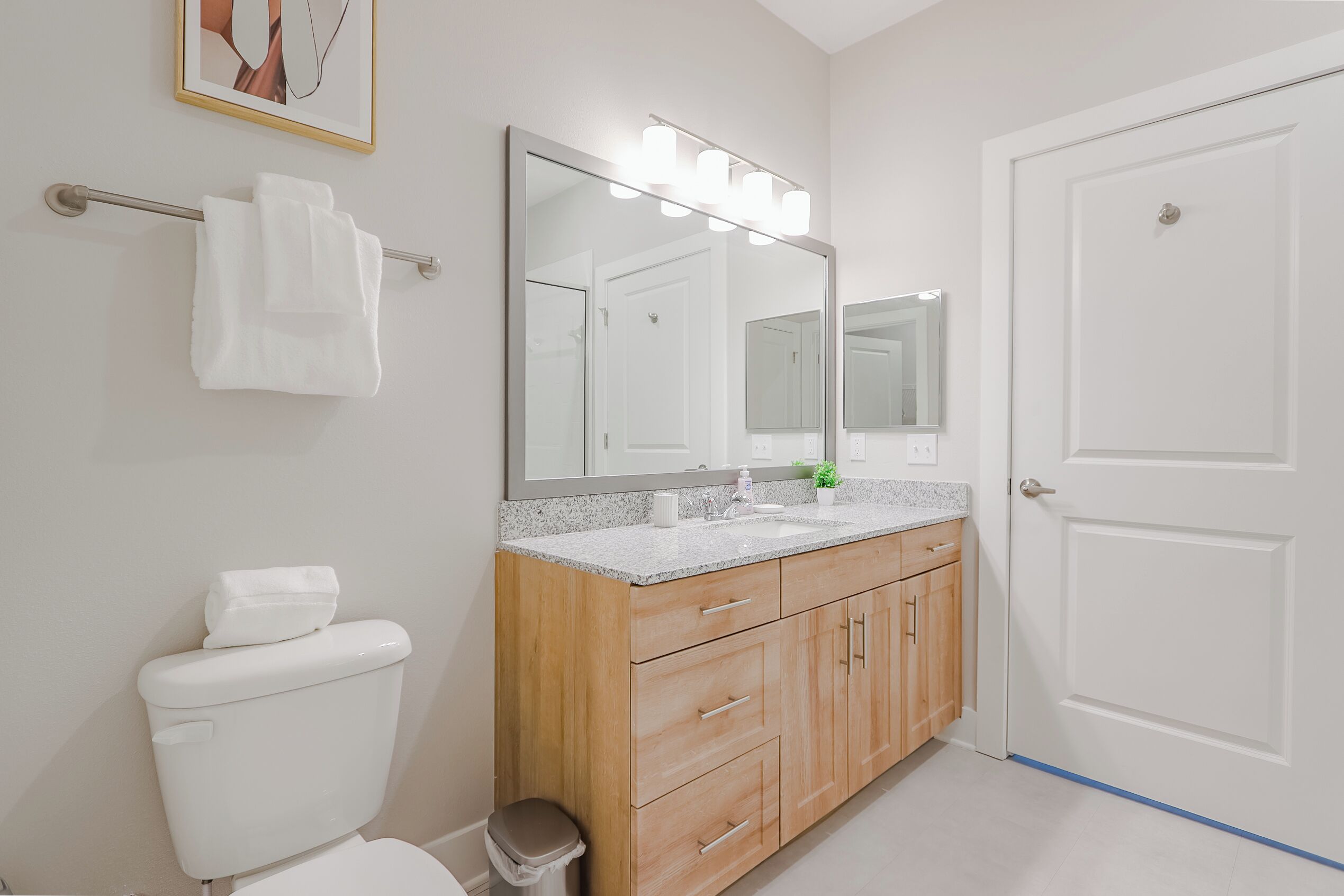 Een badkamer met toilet, wastafel, een wastafelmeubel met spiegel en een handdoekhouder.