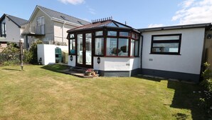 A house with a conservatory, a white exterior, and a small garden. - Goetra (Harlech)