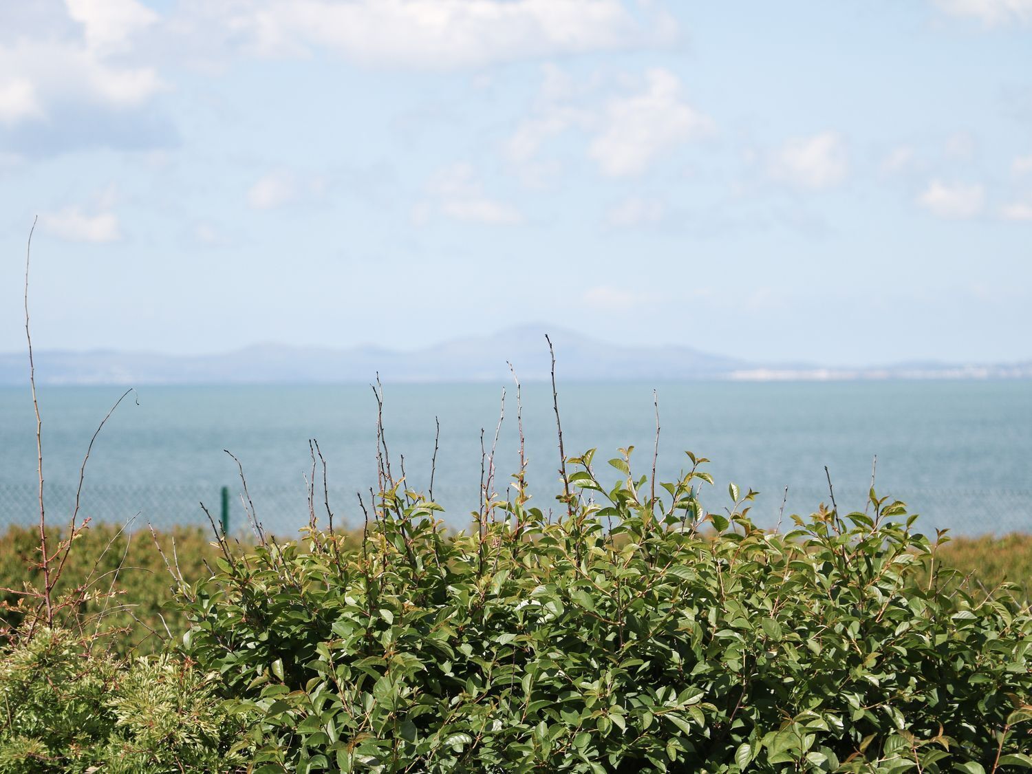 A coastal landscape with a view of the sea and distant mountains.
