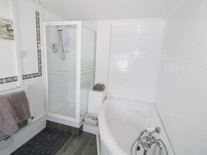 Un bagno moderno con doccia vetrata, una vasca freestanding e un tappetino da pavimento dal motivo scuro.