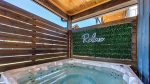 A hot tub area with a wooden slatted ceiling and a wall with a 'Relax' sign. - Little Haven Chalet (Pigeon Forge)