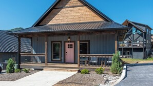 A wooden cabin with a front porch, a door marked with the number 591, and a small garden area. - Little Haven Chalet (Pigeon Forge)