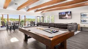 A spacious living area with a pool table, a sofa, and a dining set. - Landing Apartments Near AT&T Stadium & Six Flags (Arlington)