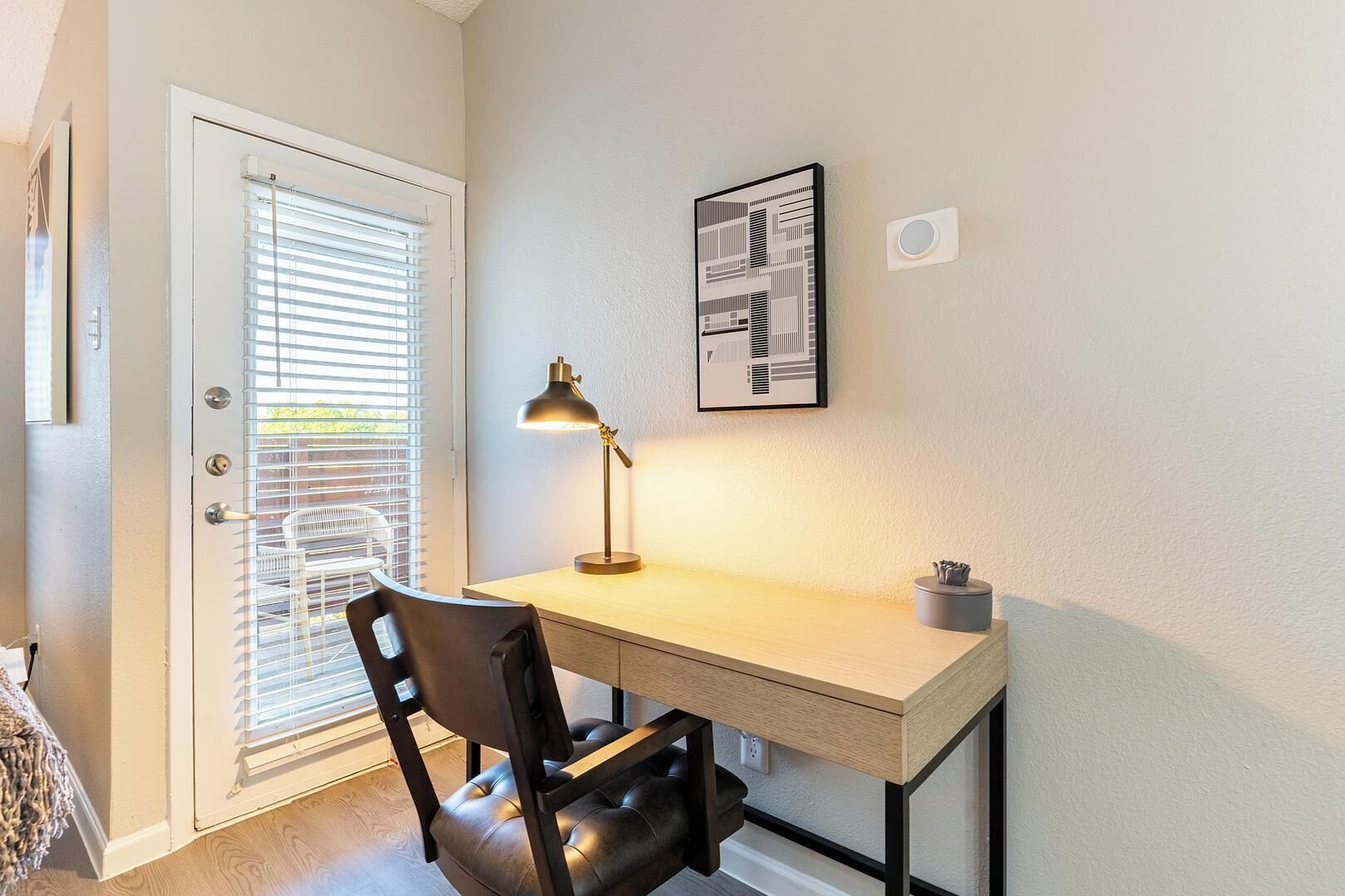 A small office space with a desk, chair, and a wall-mounted lamp.