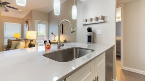 A modern kitchen with a stainless steel sink, pendant lights, and a built-in coffee maker. - Landing Apartments Near AT&T Stadium & Six Flags (Arlington)