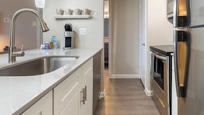 A modern kitchen with stainless steel appliances, a built-in sink, and a coffee maker. - Landing Apartments Near AT&T Stadium & Six Flags (Arlington)