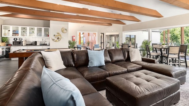 A spacious living area with a large sectional sofa, a dining area, and a kitchen in the background. - Landing Apartments Near AT&T Stadium & Six Flags (Arlington)