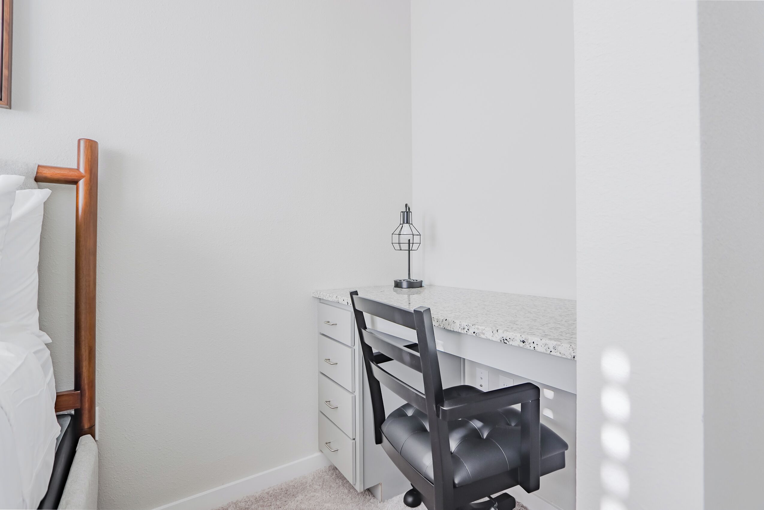 Une petite pièce propre, avec un bureau blanc, une chaise et un radiateur en bois.