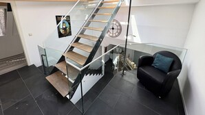 Ein modernes Interieur mit einer Glasstiege, einem schwarzen Ledersofa und einer Wanduhr.
