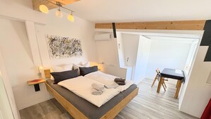Ein modernes Schlafzimmer mit einem hölzernen Bett, Nachttischen, einem Schreibtisch und einem Sessel.
