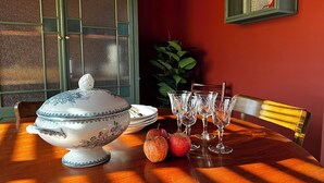Un tavolo da pranzo con una zuppiera, piatti, bicchieri e mele.