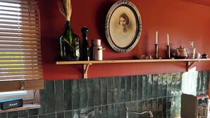 Una cucina con un piano di lavoro in legno, un lavello bianco, una radio d'epoca e una piastra decorativa con un ritratto.