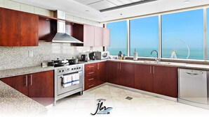 A modern kitchen with granite countertops, stainless steel appliances, and wooden cabinets. - Premium Iconic Beachside JBR Stay (Dubai)