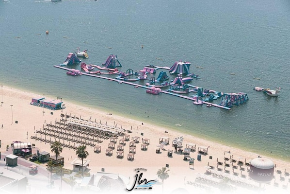 A beach resort with a long pier featuring water slides and a beach area with rows of sun loungers. - Premium Iconic Beachside JBR Stay (Dubai)