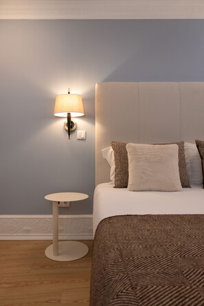 Ein Hotelzimmer mit einem Bett, einem runden Beistelltisch, einer Wandlampe und einer strukturierten Wand.