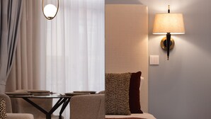 Une chambre d’hôtel moderne avec un coin repas, un lit recouvert d’un jeté rouge et une lampe fixée au mur.