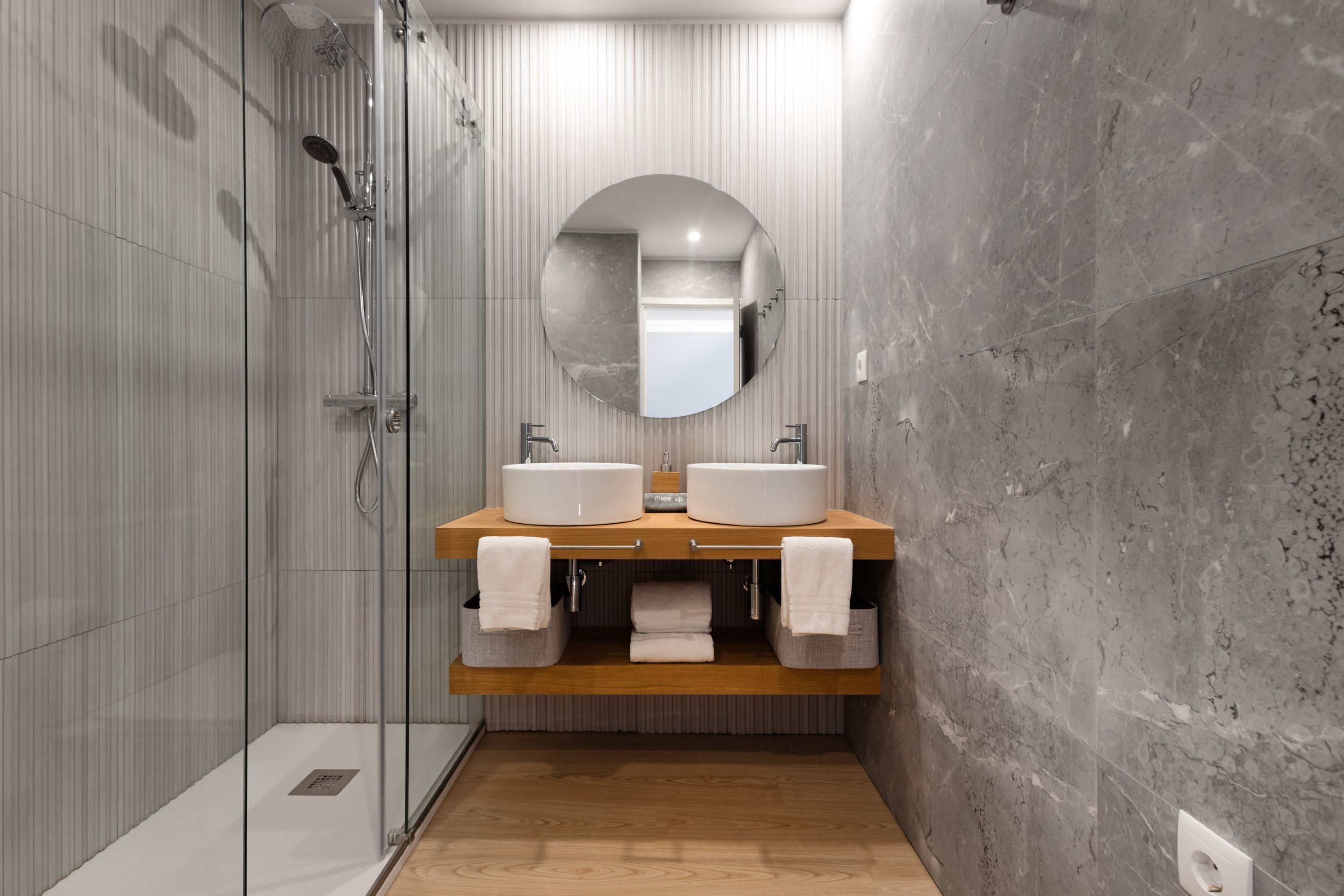 A modern bathroom with two sinks, a large mirror, and a shower.