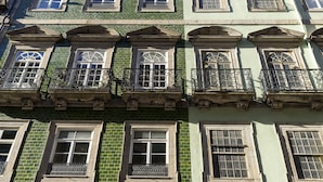 Un edificio de varios pisos con fachada verde, múltiples ventanas con barandillas metálicas y un estilo arquitectónico uniforme.