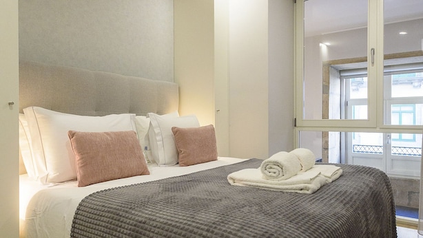 Una habitación de hotel moderna con una cama grande, un cabecero y una ventana con vistas.