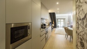 A modern kitchen with stainless steel appliances, a dining area with a light wood floor, and a staircase leading to another level. - RA - S o Jo o 3 in Oporto (Porto)